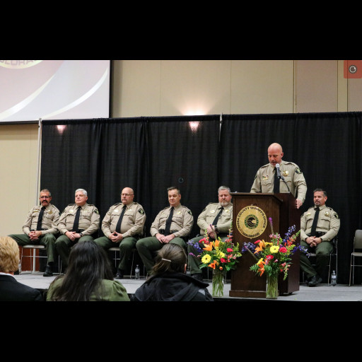 Sheriff Todd Rowell speaks at the Mesa County Sheriff's Office award ceremony with members of the Admin Staff behind him on stage.