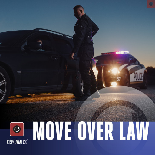 A police officer speaking to the driver of a pulled over vehicle on the roadway.