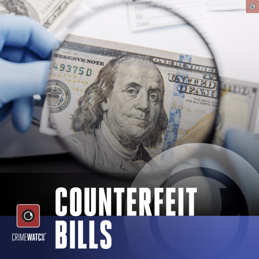 An investigator magnifying what appears to be a counterfeit dollar bill.